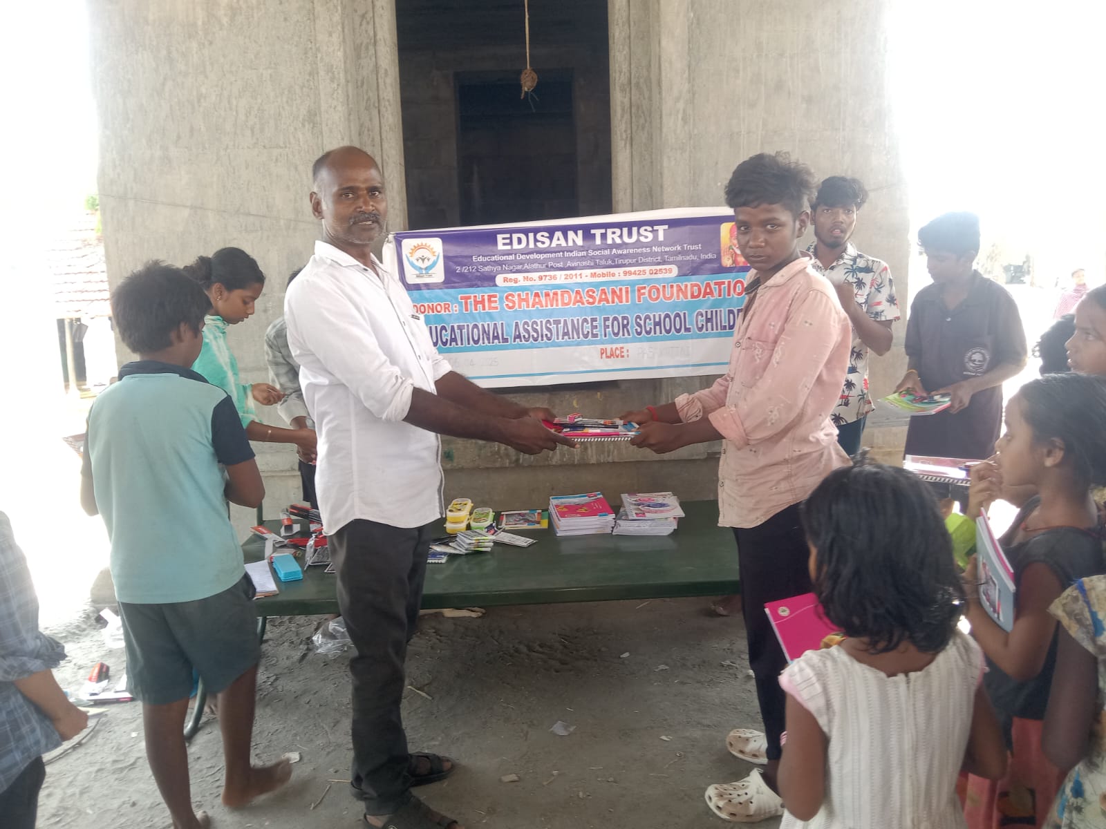 EDISAN Trust volunteer distributing school kits to children under a bridge shelter