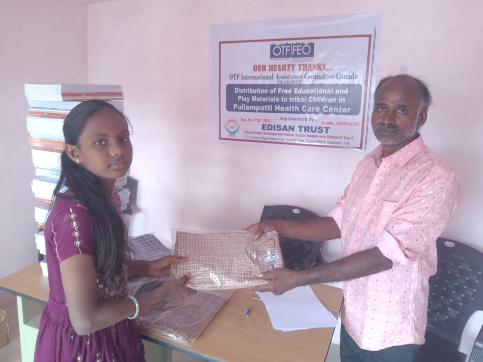 Girl receiving folded school uniform fabric at Puliampatti Health Care Center