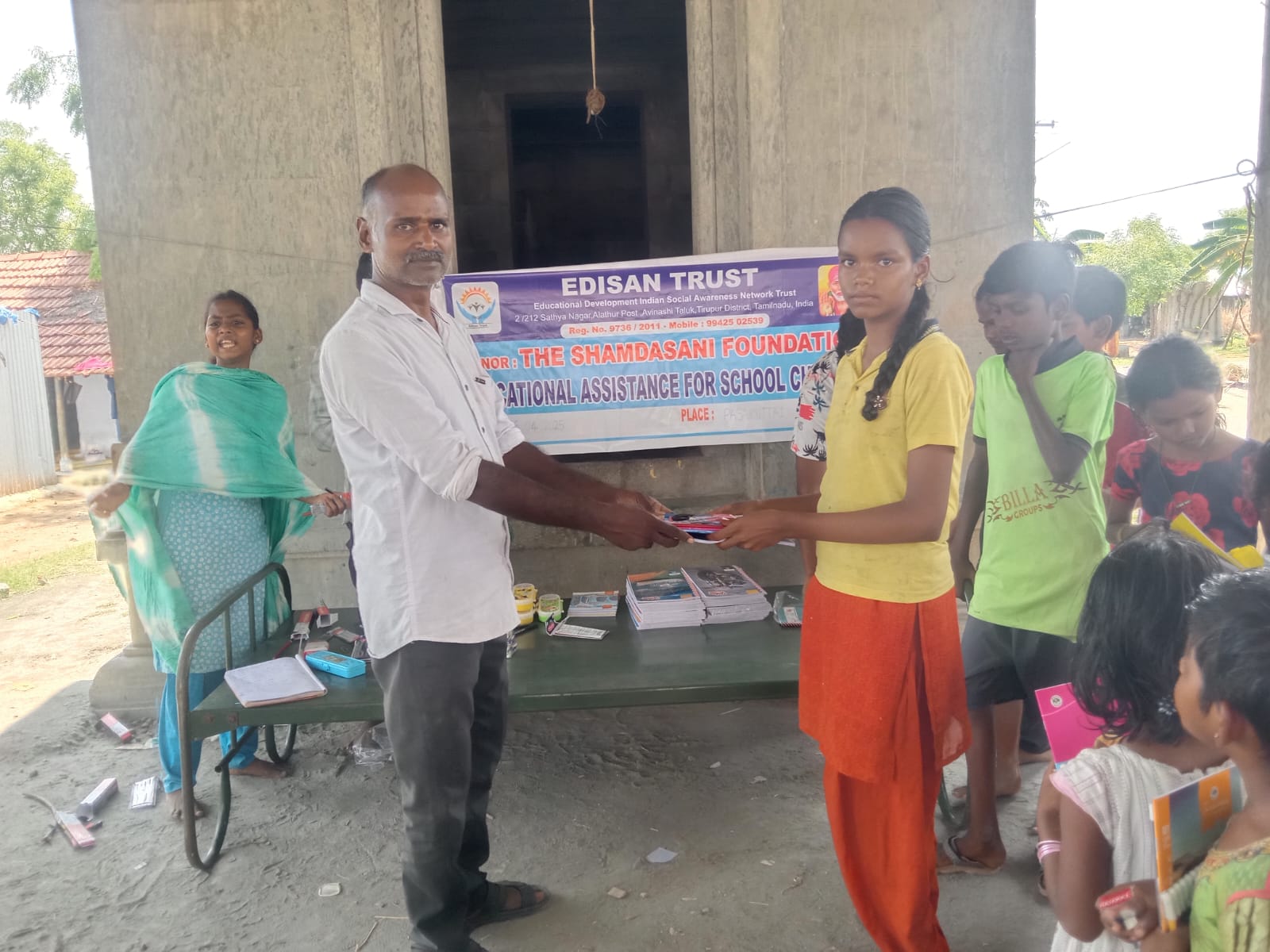 Child receiving school stationery kit from EDISAN Trust volunteer