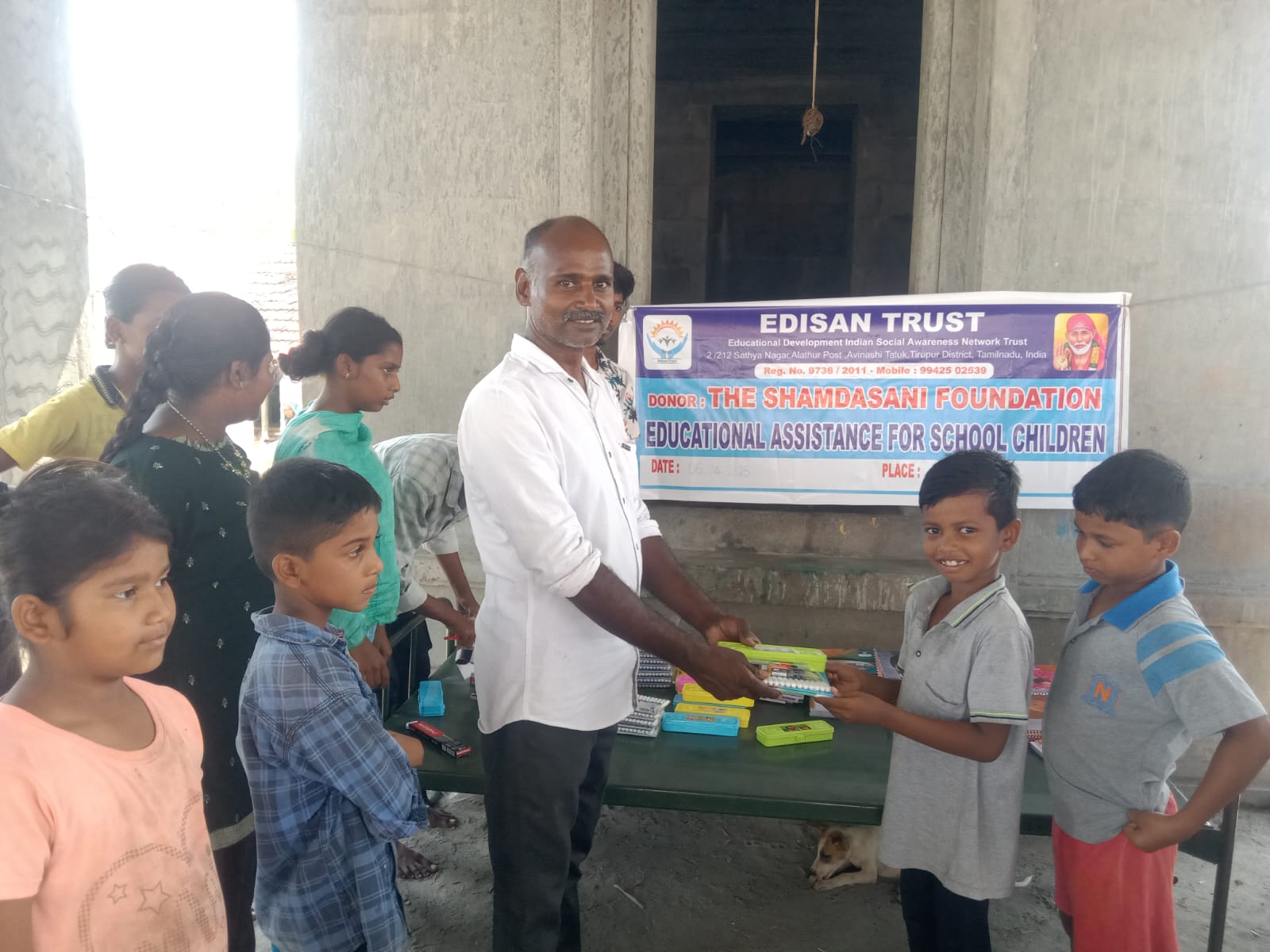 Volunteer handing school materials to a girl under the shelter