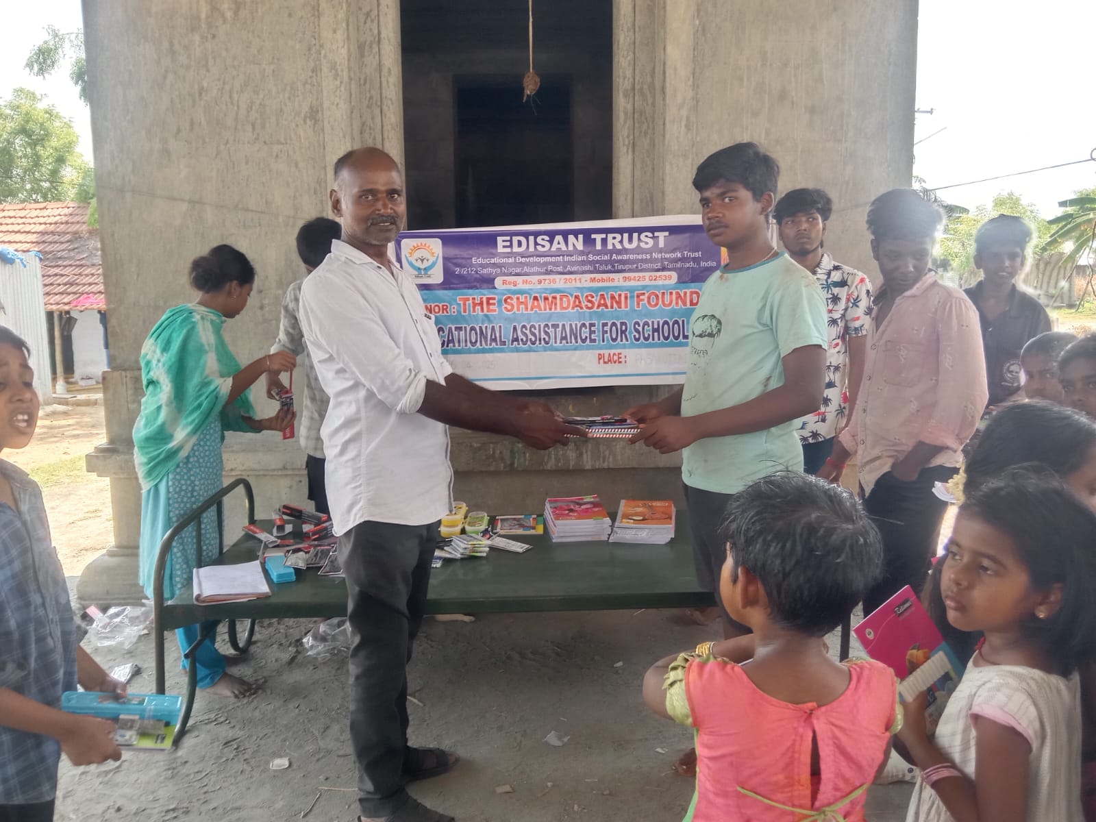 Boy in mint green shirt receiving school kit, dated 6 April 2025