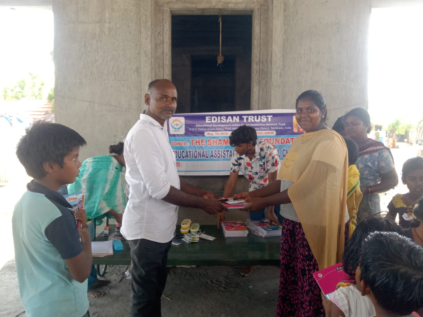 Volunteer handing school materials to a mother on behalf of her children